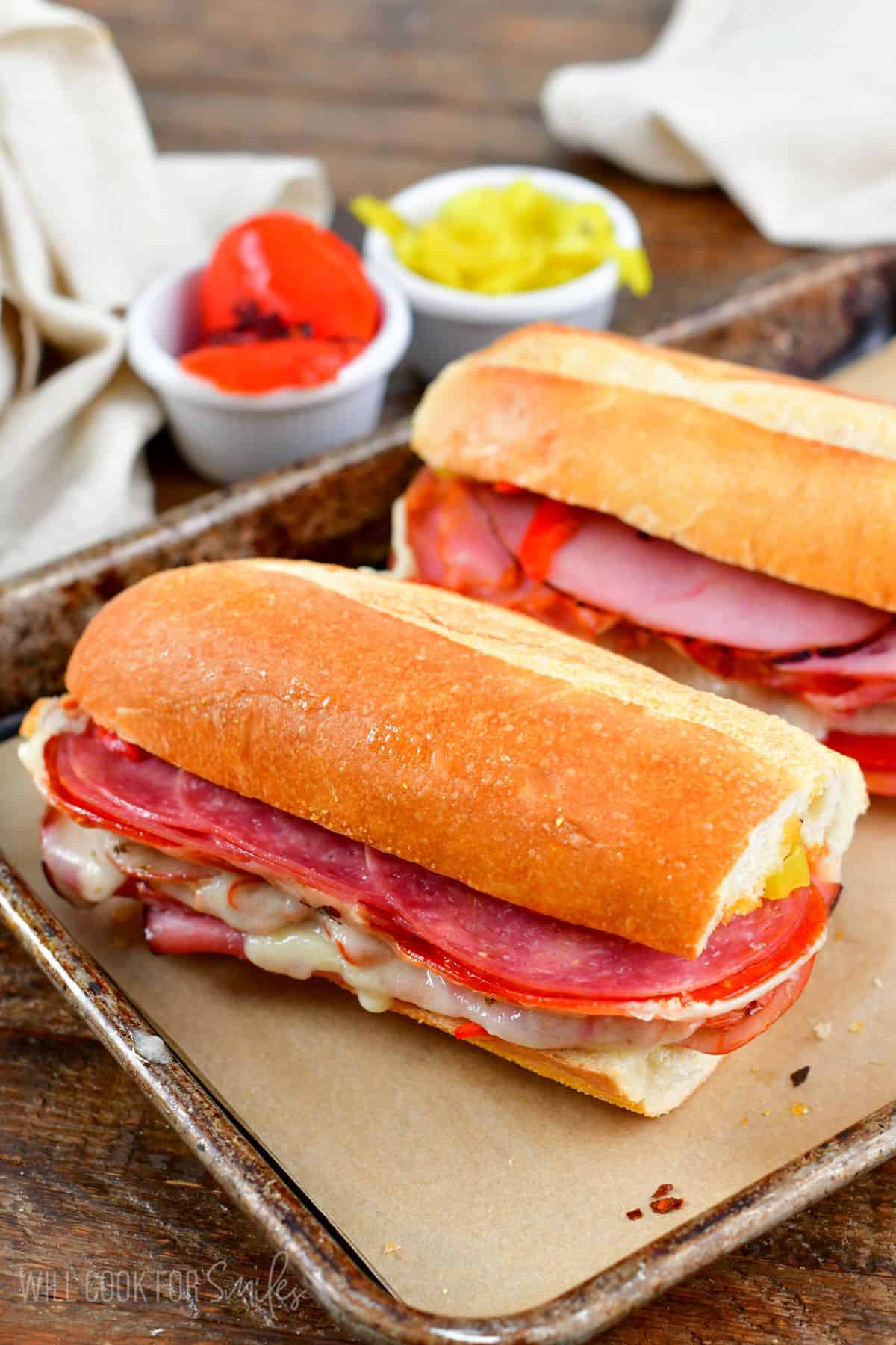 Two Italian subs on a baking sheet lined with parchment paper.