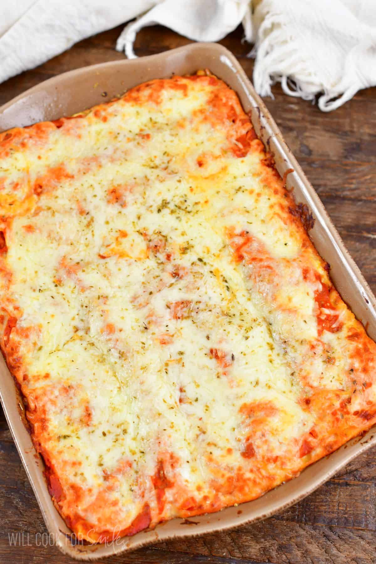 lasagna in a baking dish on a wood surface.