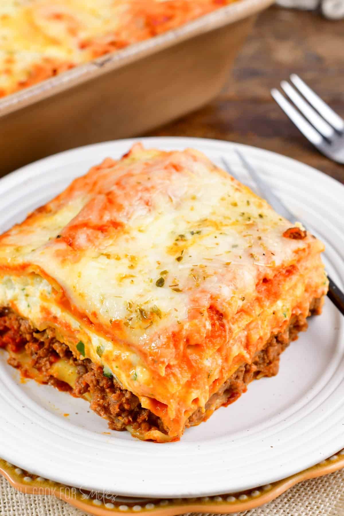 a slice of lasagna on a stacked white and brown plate.