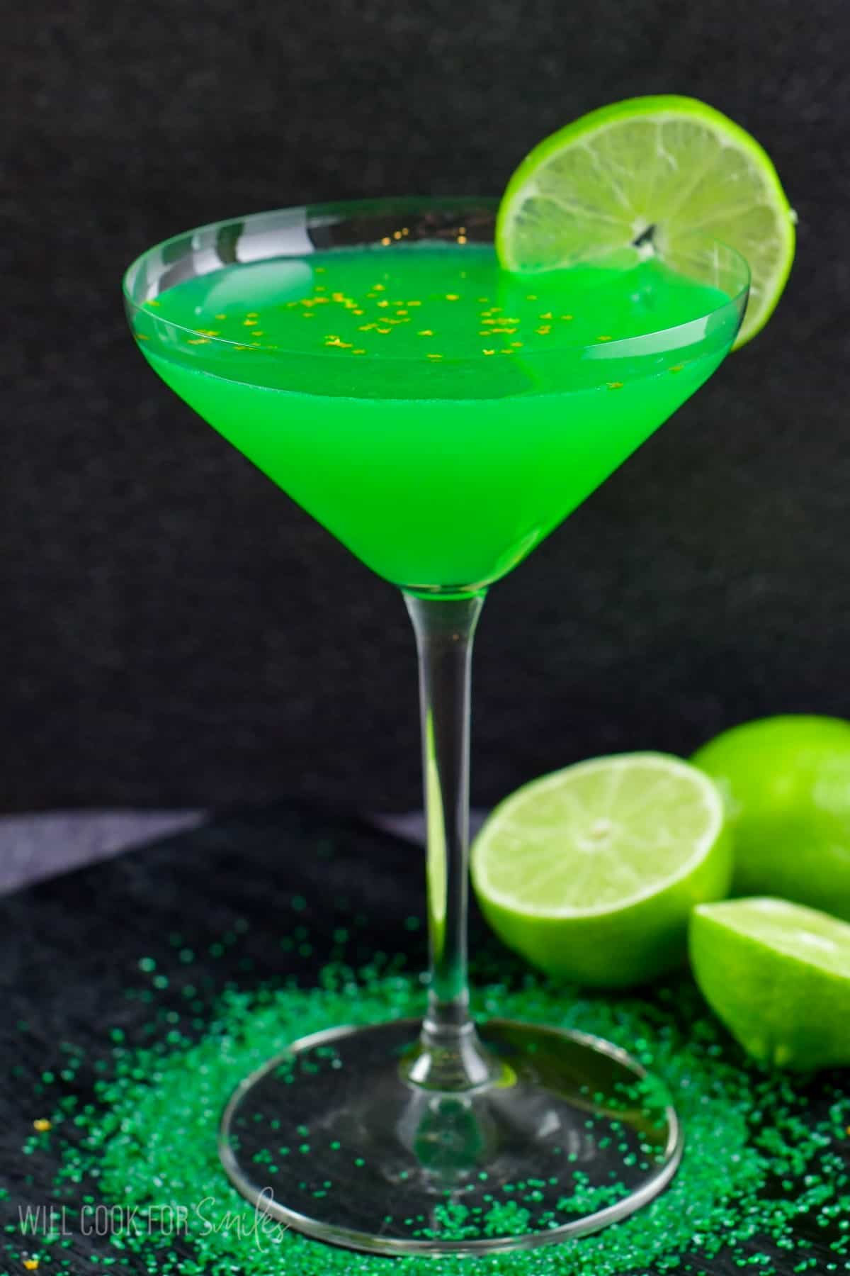 lime martini in a glass with a lime wedge on the side of the glass and sprinkles at the base of the glass.