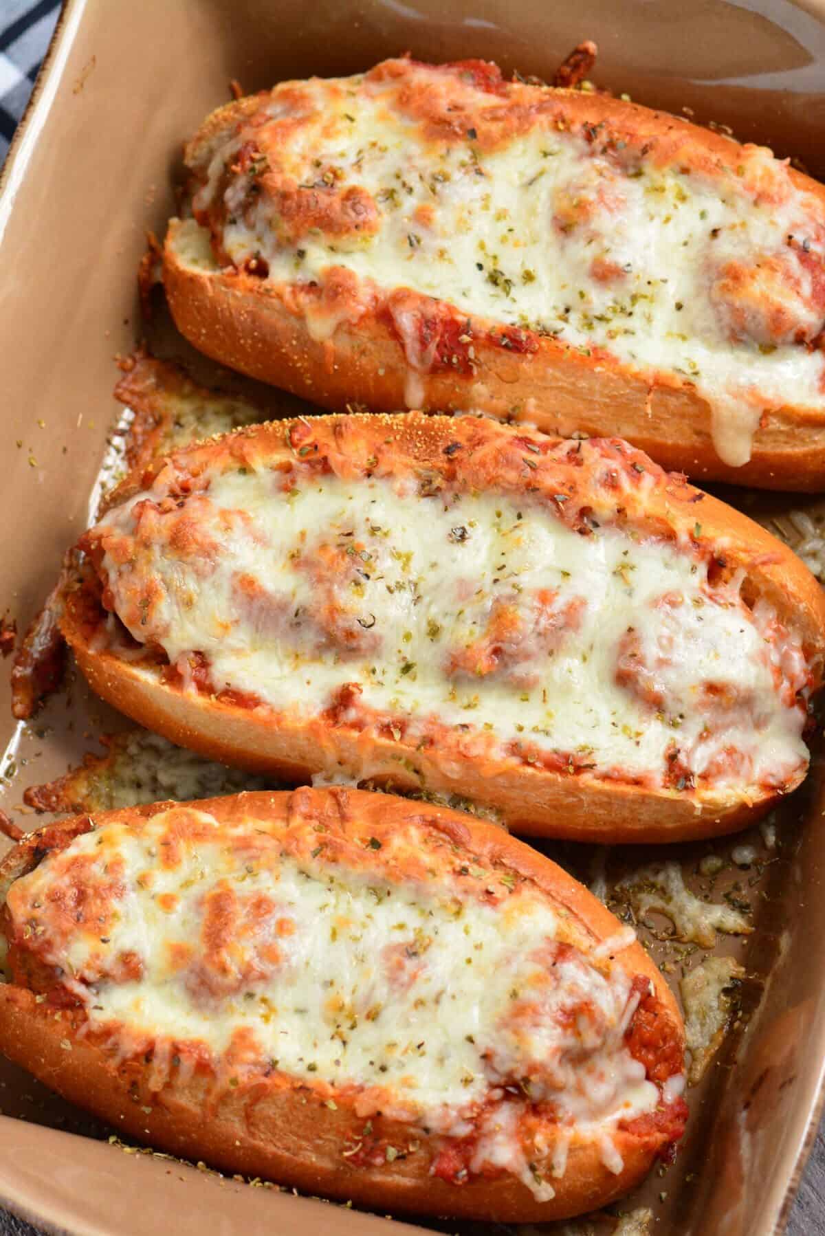 three meatballs subs in a baking dish.