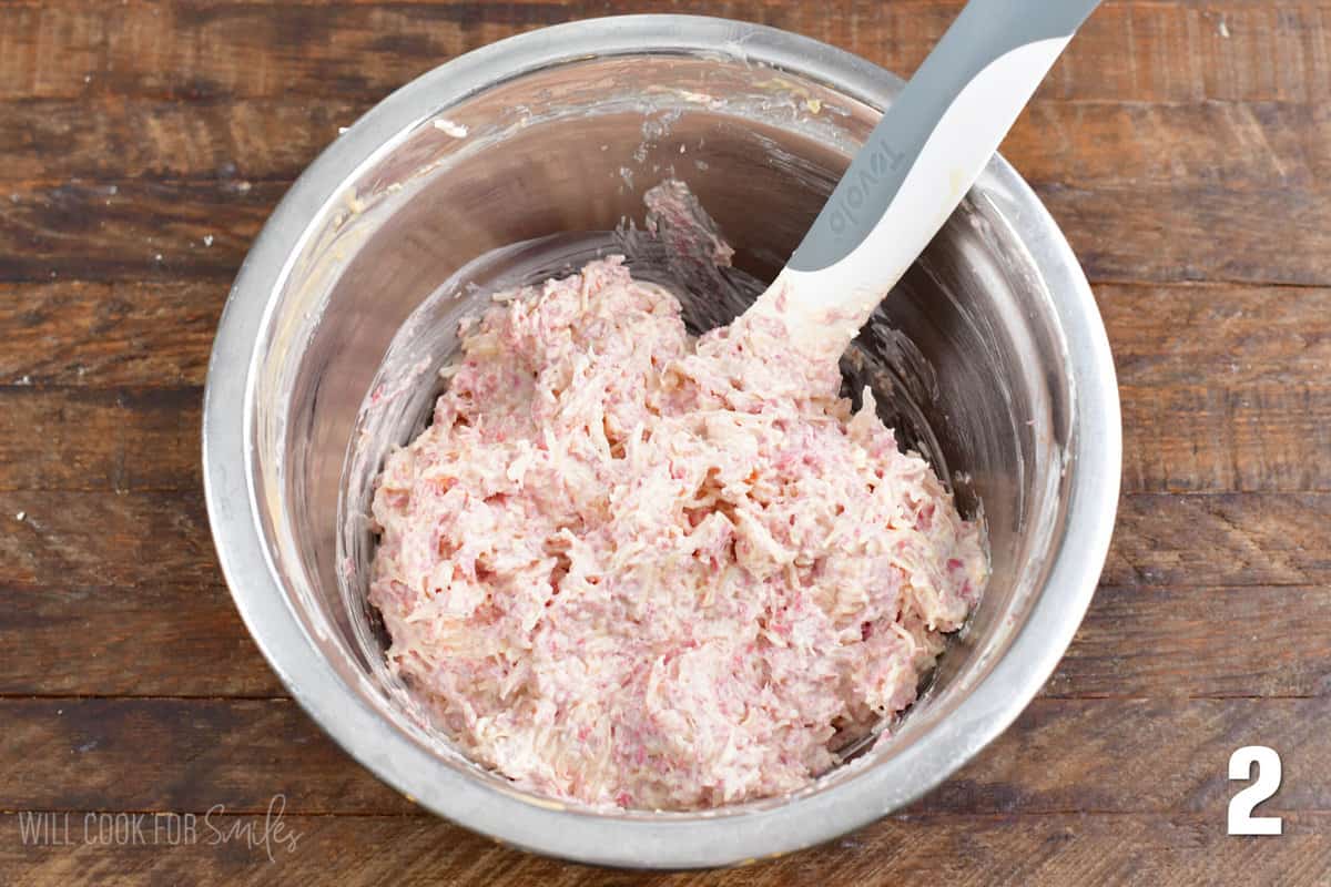 Reuben dip ingredients mixed up in a metal bowl with a plastic spoon in the bowl.