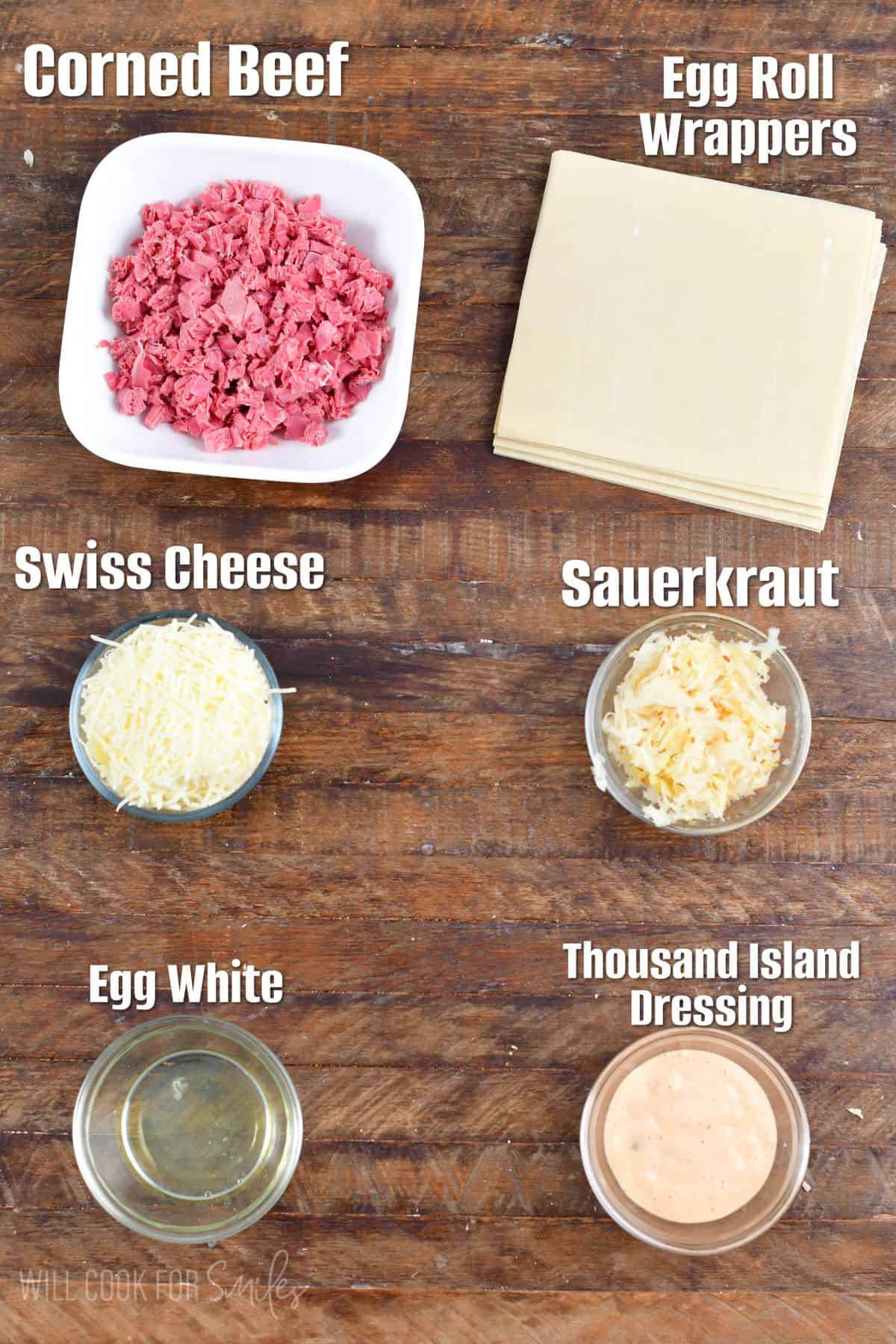 Labeled ingredients for reuben egg rolls on a wood surface.