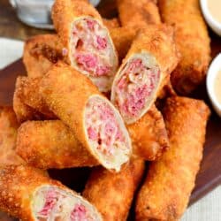 Reuben egg rolls with several cut in half and places on a wood tray.