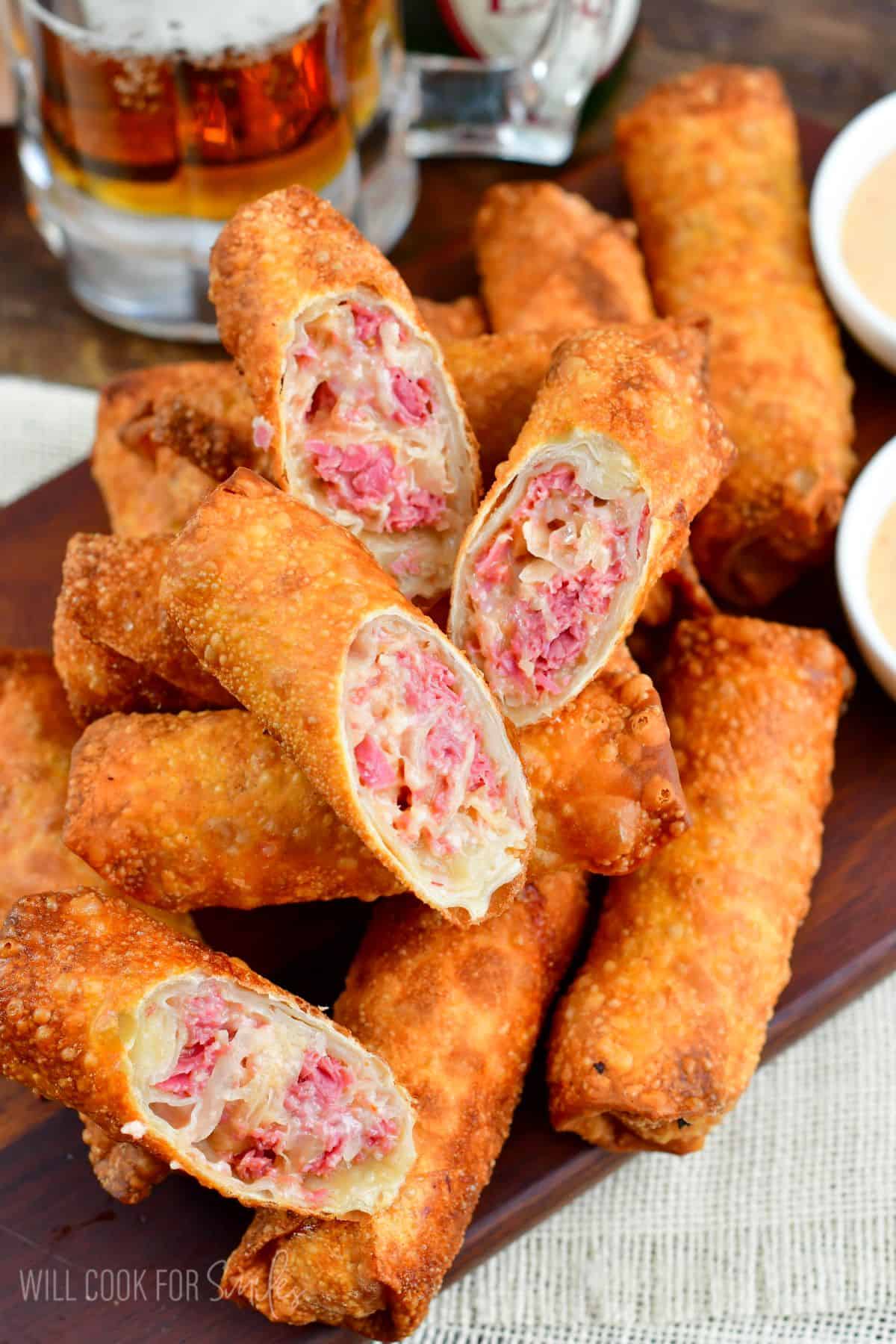 Reuben egg rolls with several cut in half and places on a wood tray.