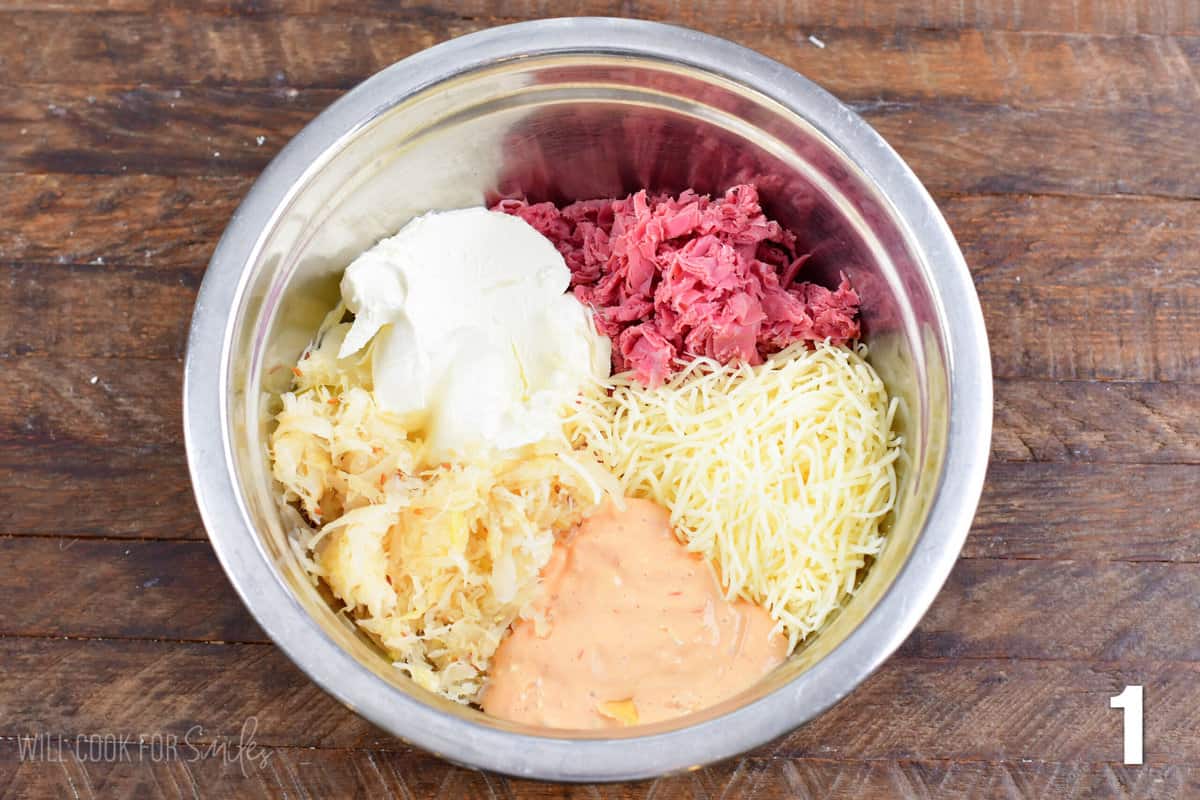 Ruben dip ingredients in a bowl on a wood surface.