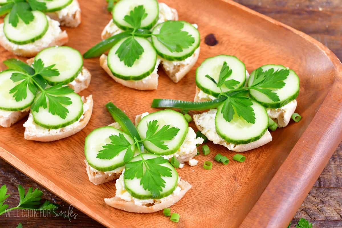 shamrock sandwhiches on a wood tray with green onions as garnish.