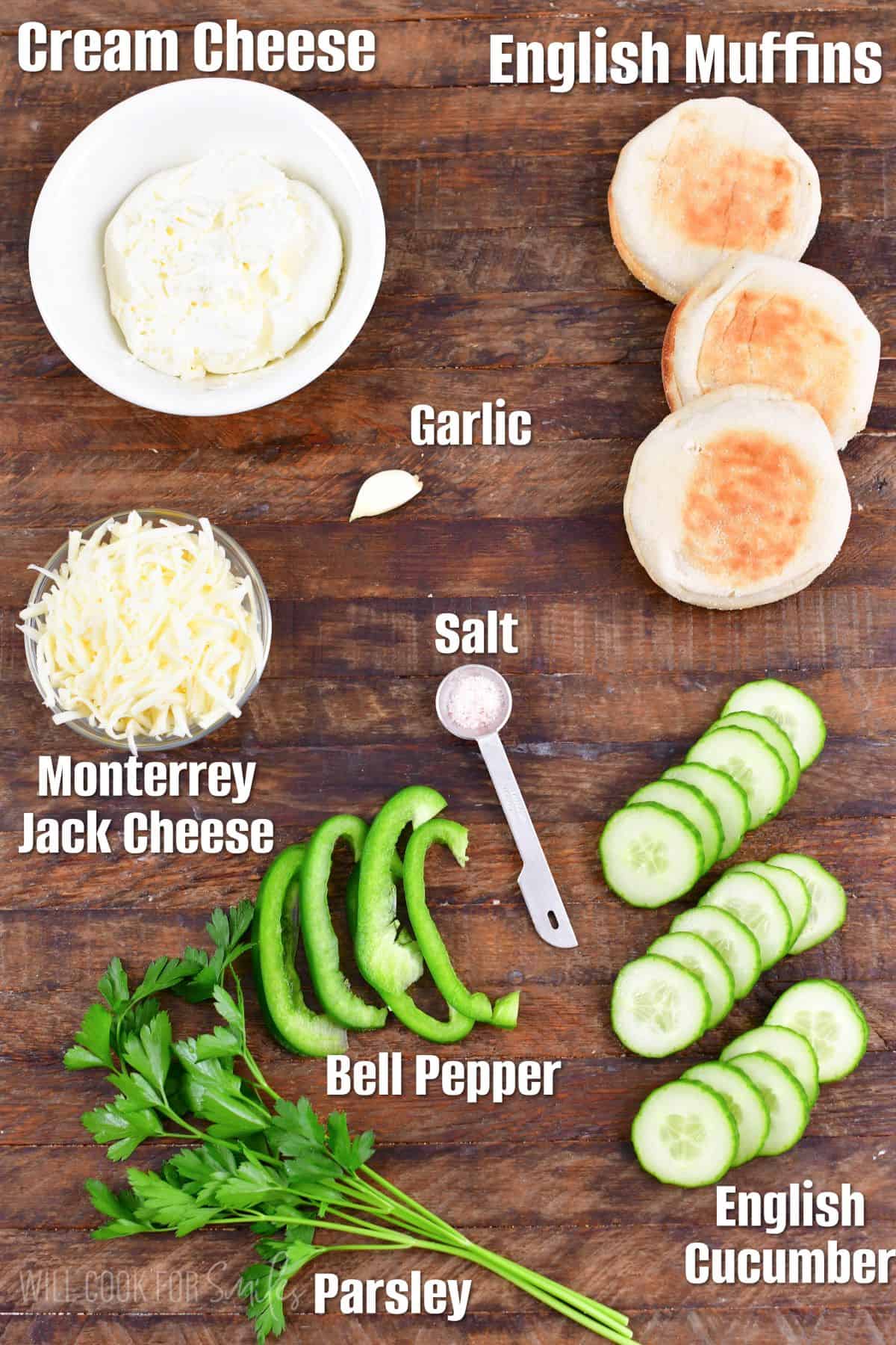 Labeled ingredients for shamrock cucumber sandwiches on a wood surface.