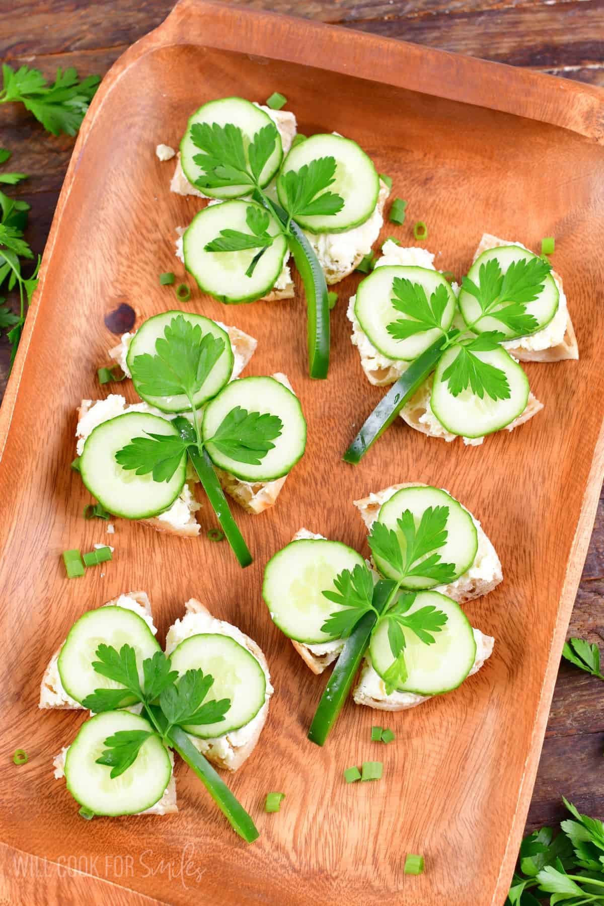 Shamrock cucumber sandwiches on a wood platter.