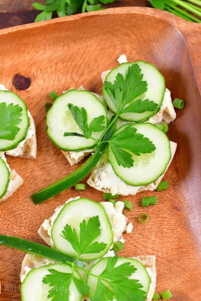 Shamrock sandwiches on a wood plater with green onions as a garnish around them.