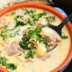 Zuppa Toscana soup in a bowl with a spoon scooping some out.
