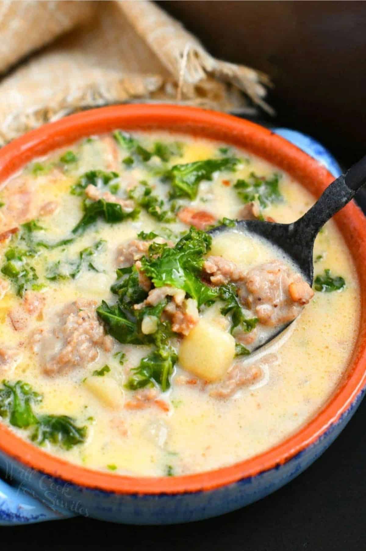 Zuppa Toscana soup in a bowl with a spoon scooping some out.