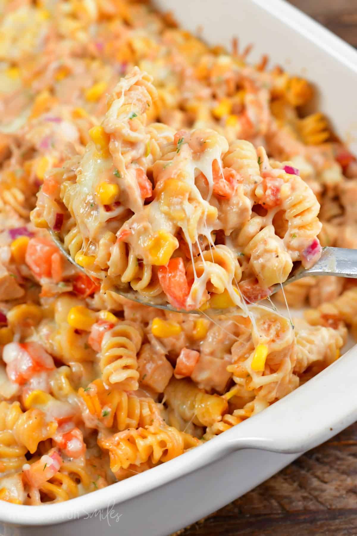 BBBQ ranch chicken pasta bake scooped out on a spoon and the rest in a casserole dish,