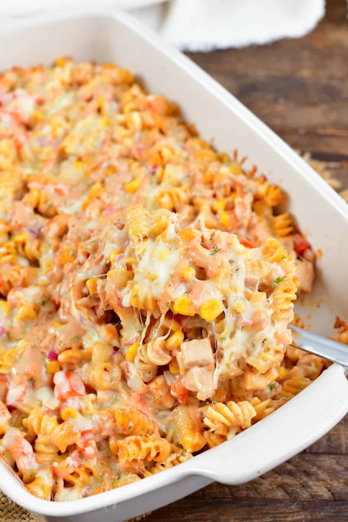 BBQ ranch chicken pasta bake being scooped out with a serving spoon.