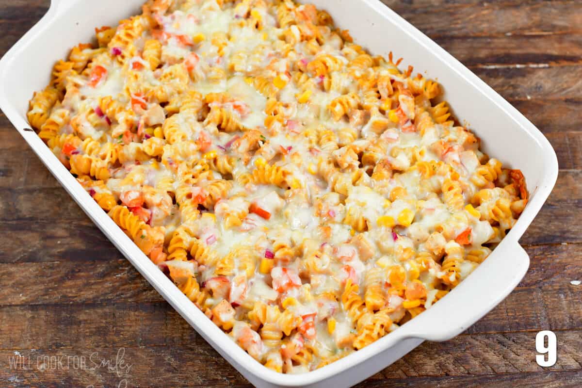 BBQ ranch chicken pasta bake in a casserole dish on a wood surface.