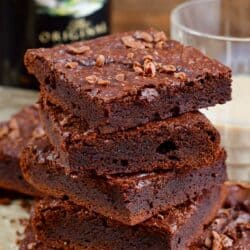 Brownies cut into squares and stacked on up on a piece of parchment.