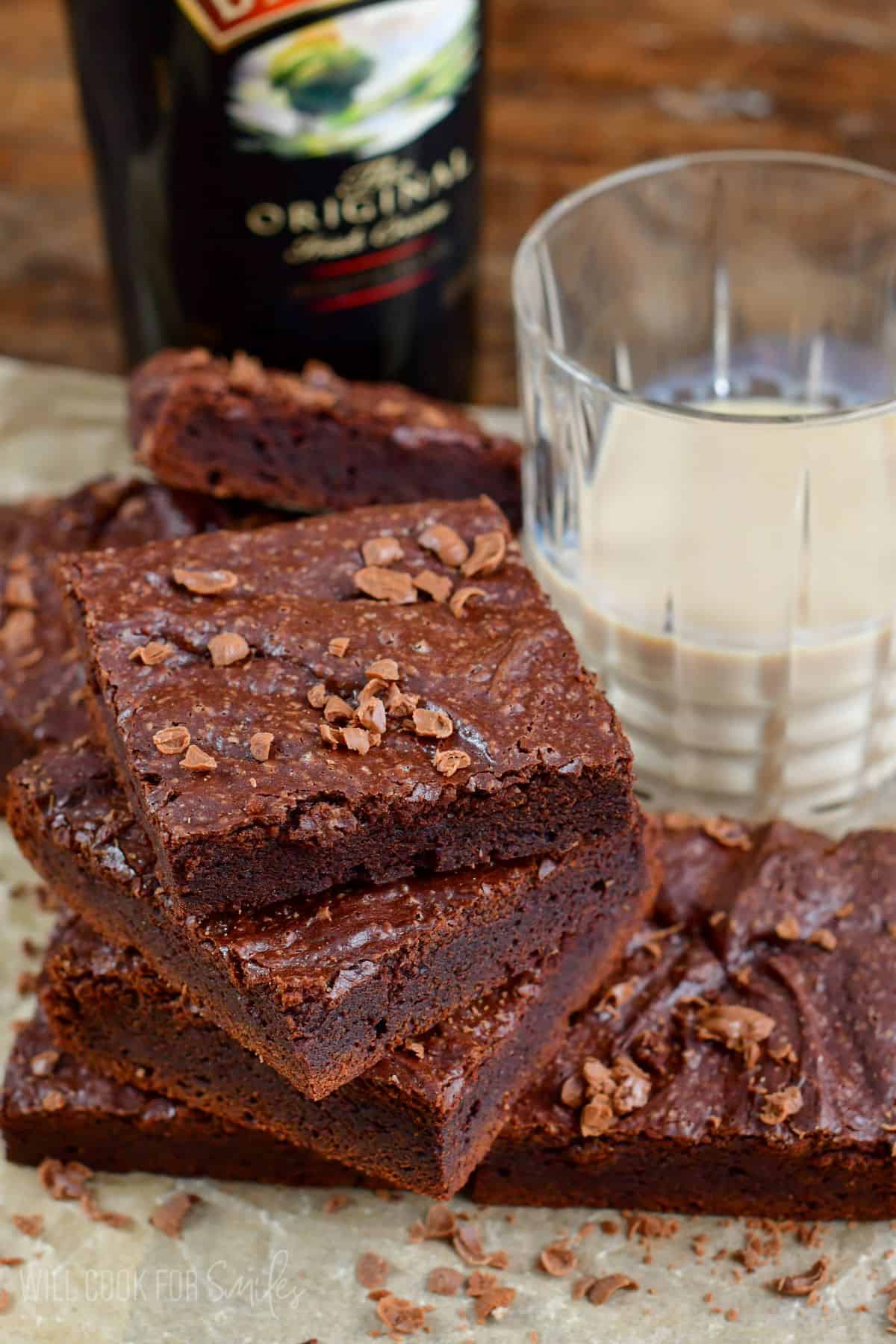 Baileys brownies stacked on a piece of parchment with chocolate shavings on top.