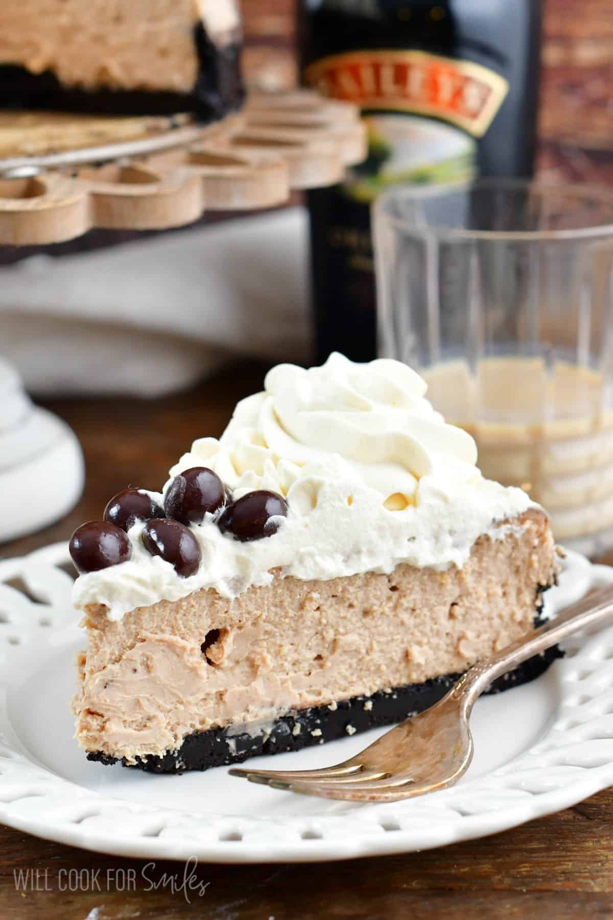 a slice of Bailey's cheesecake on a white plate with a fork.