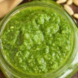 bright green basil pesto in a glass jar filled to the top.