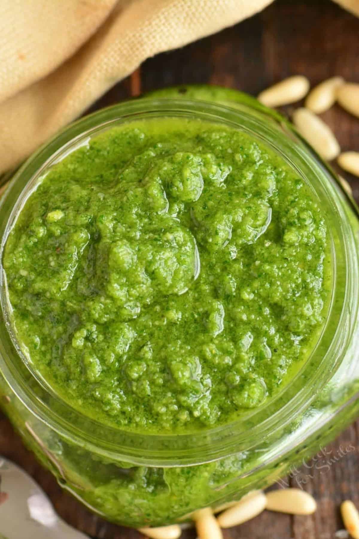 bright green basil pesto in a glass jar filled to the top.