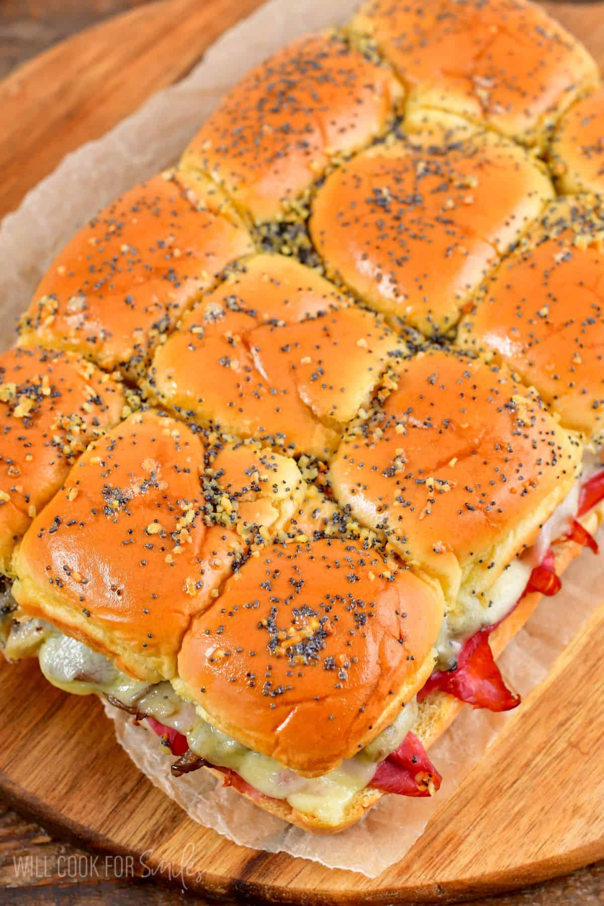 Corned beef sliders after being baked on a wood cutting board.