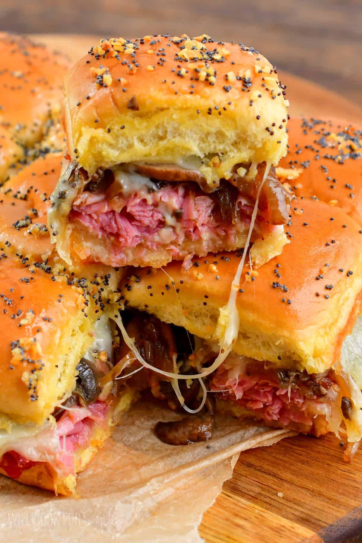 Corned beef sliders on a cutting board and one slider stacked on top.