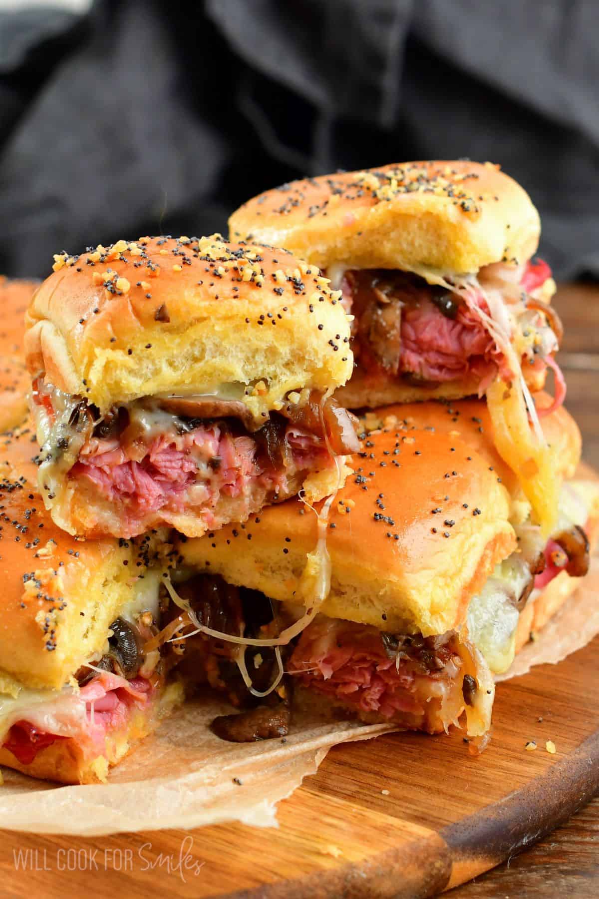 Two corned beef sliders stacked on top on a wood cutting board.