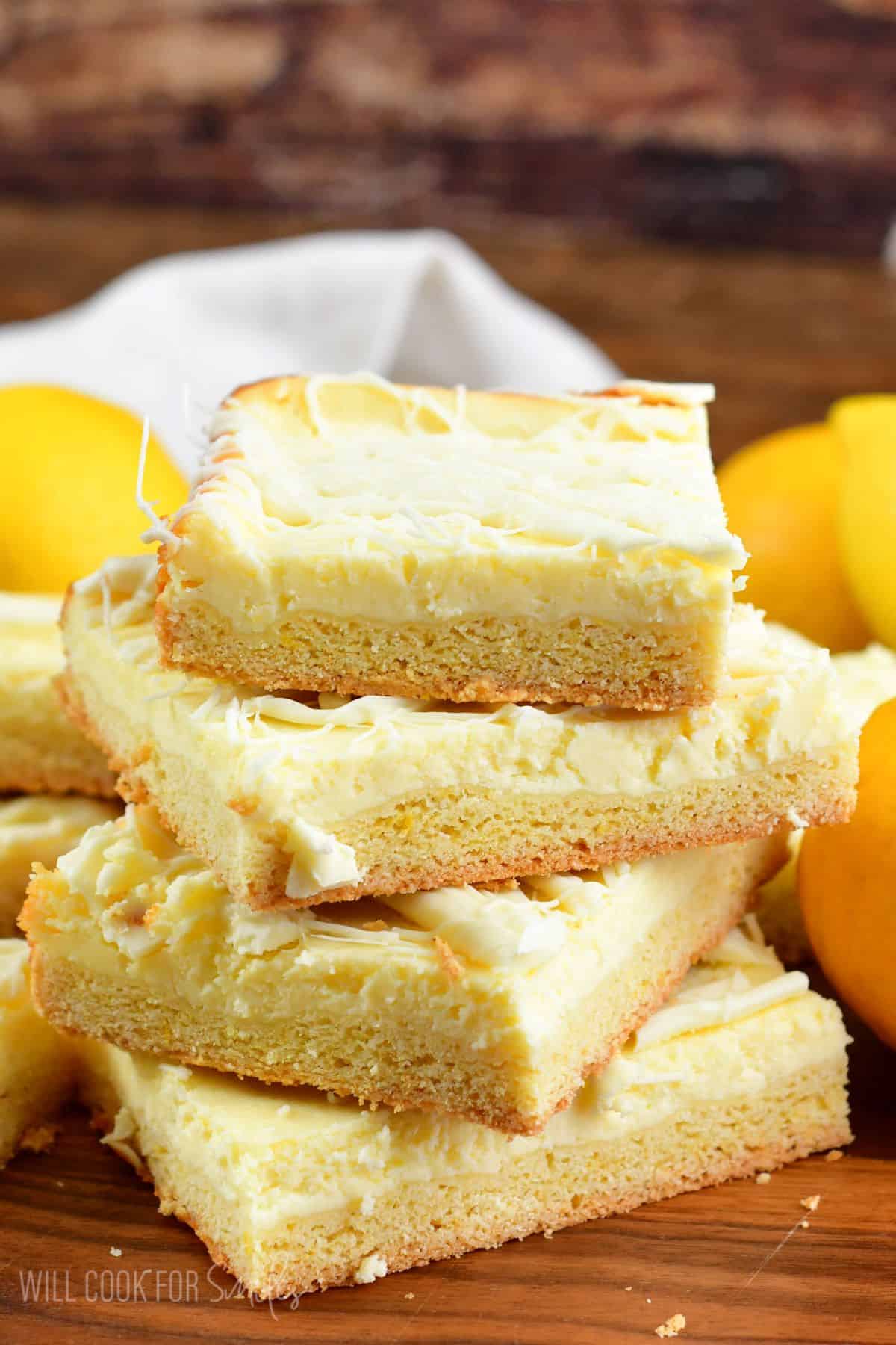 Collage of lemon cheesecake cookie bars cut into squares and staked on top of each other.