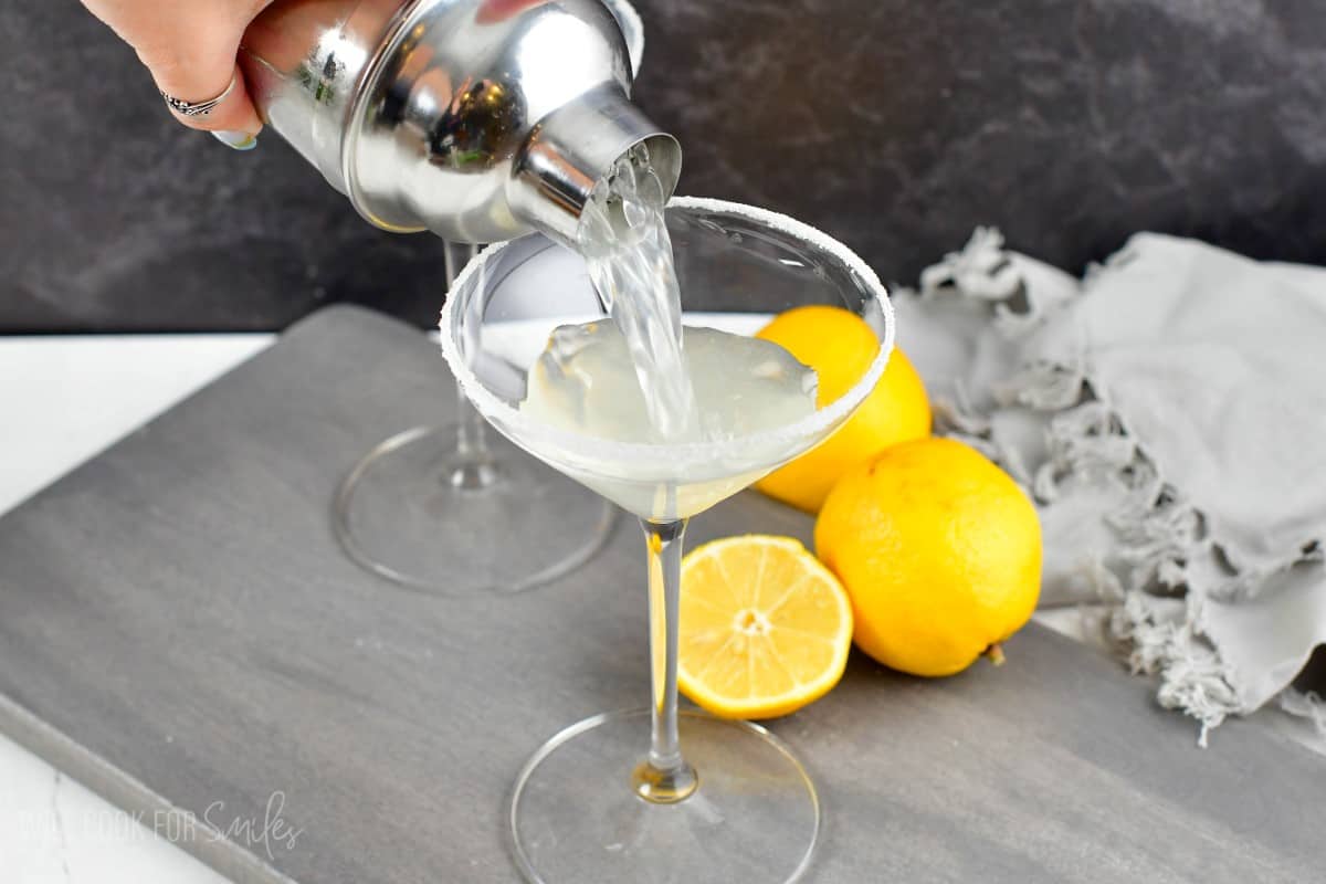 Pouring lemon drop martini into sugar rimmed glass out of the shaker.