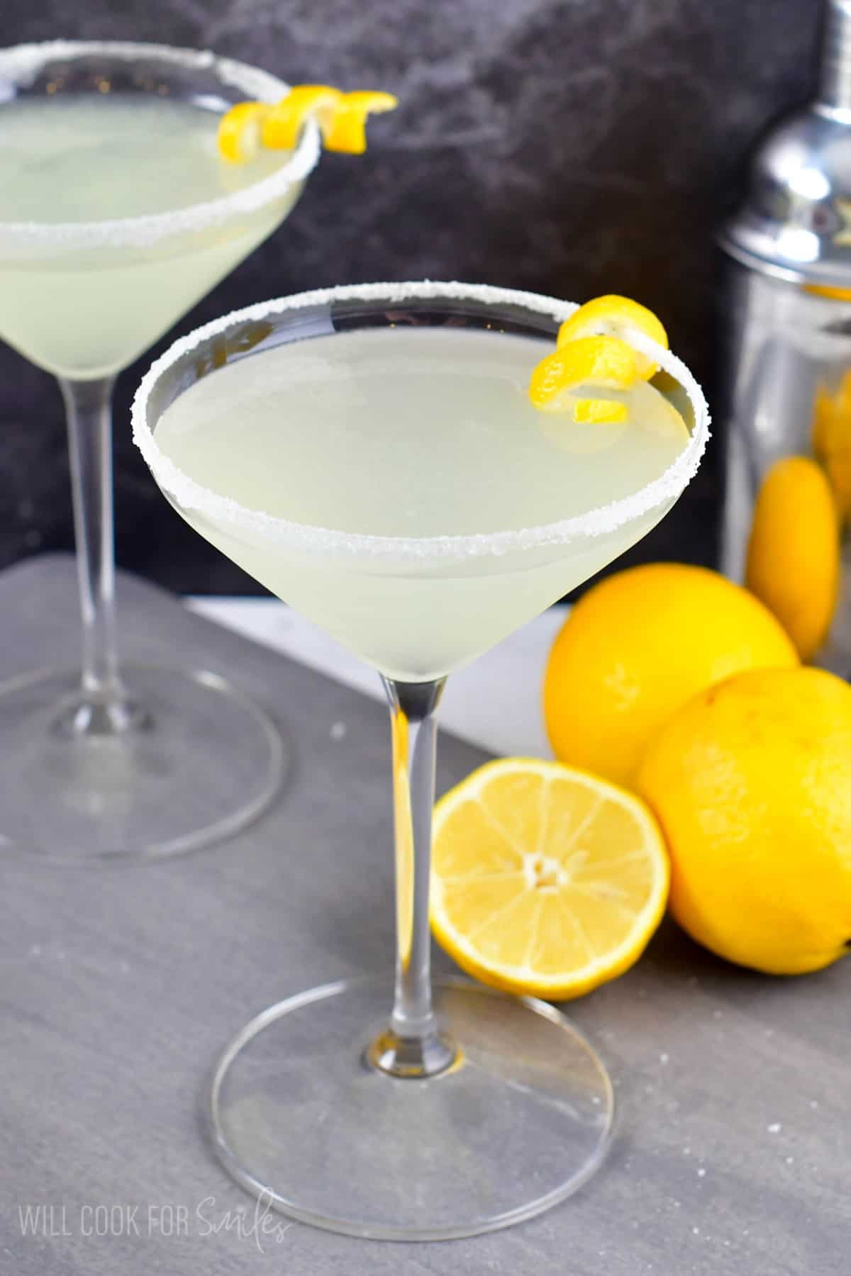 Lemon drop martini in a martini glass with sugar on the rim and a lemon twist on the side of the glass as garnish.