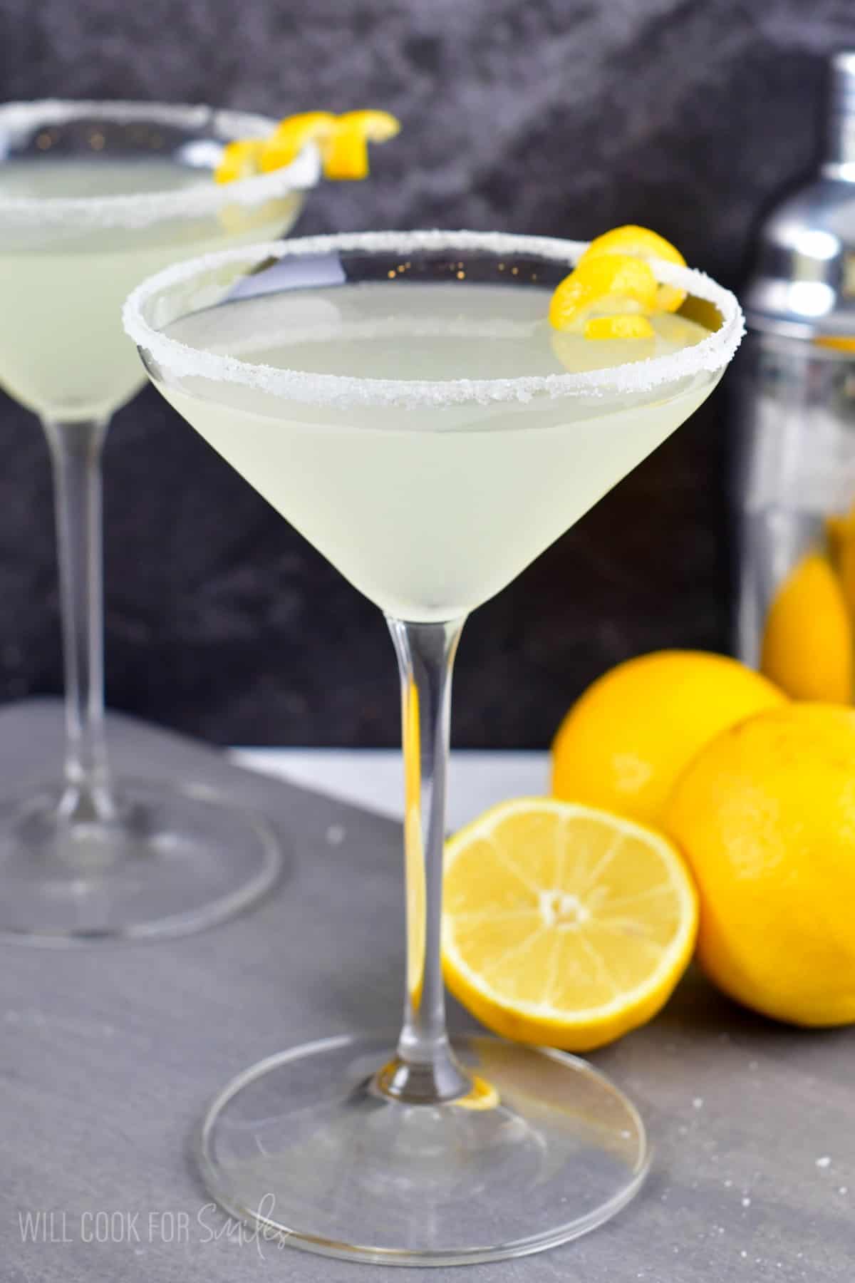 two lemon drop martini's in a martini glass with a lemon twist on the side of glass as garnish.