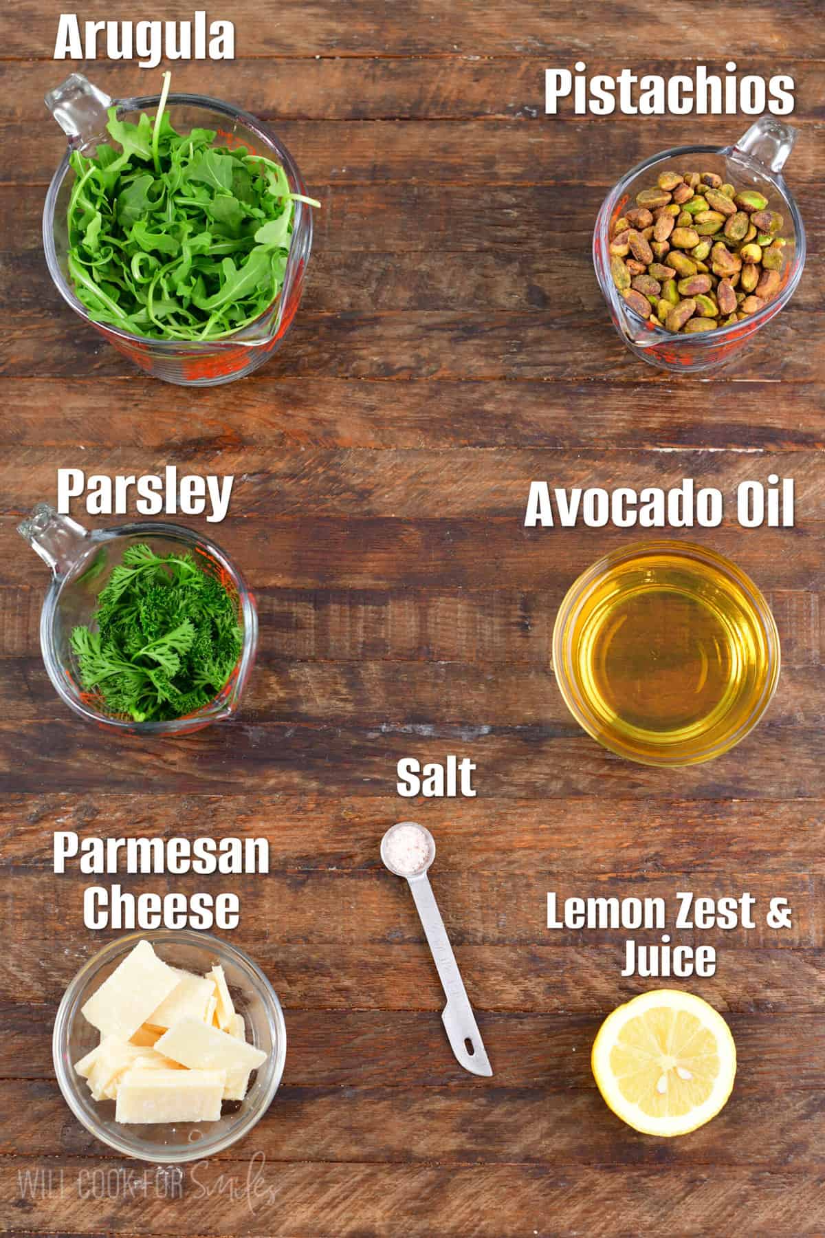 Labeled ingredients for lemon pistachio arugula pesto on a wood surface.