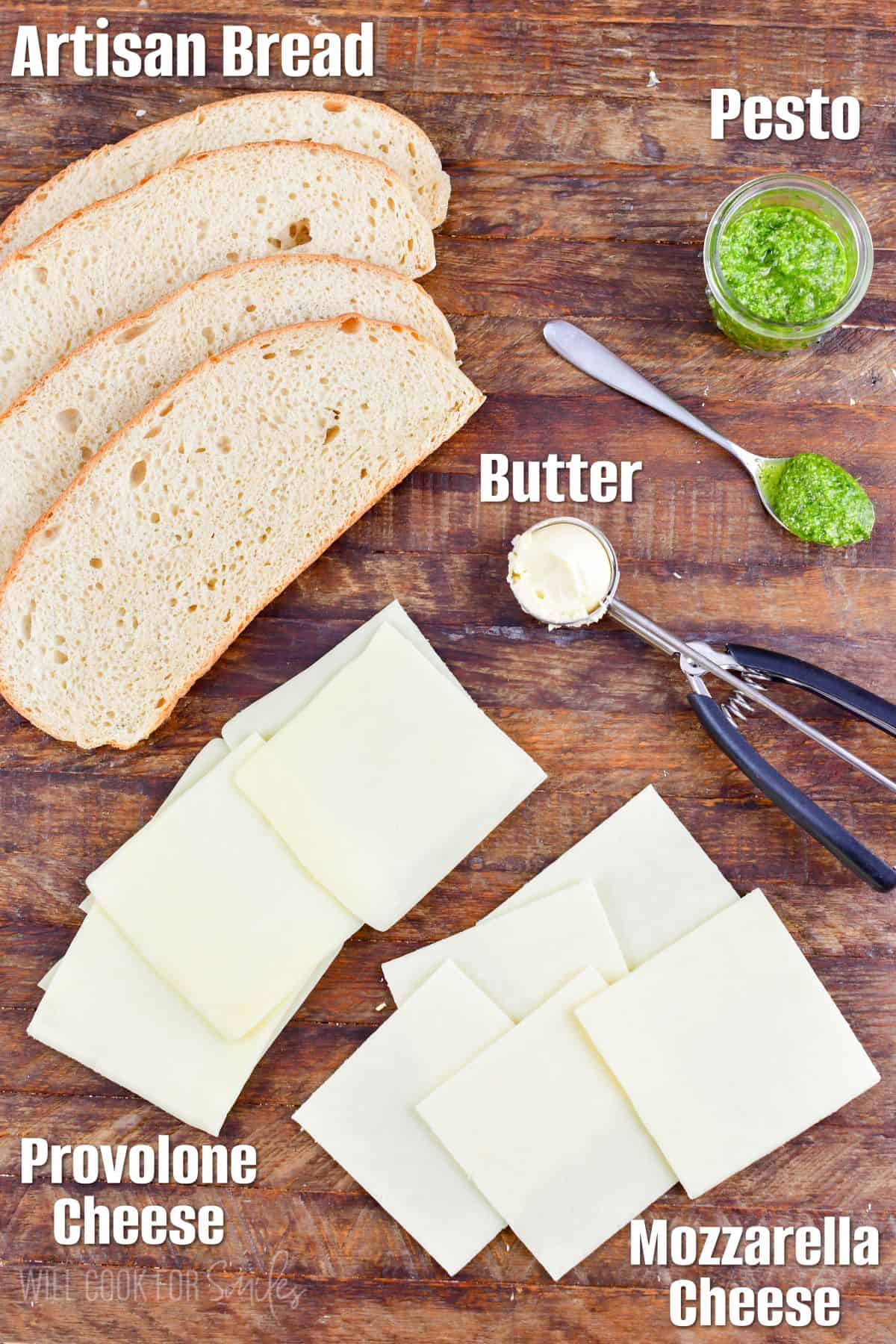 Ingredients for for pesto grilled cheese sandwiches on a wood surface.