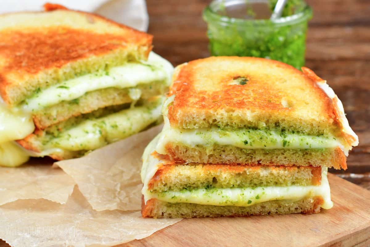 Two pesto grilled cheese sandwiches cut in half in two stacks.