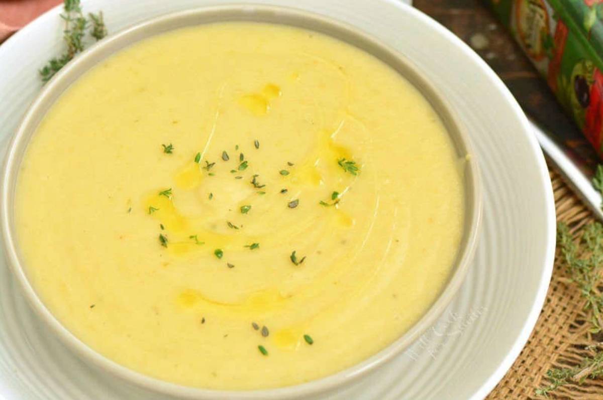 Potato leek soup in a bowl with rosemary sprinkled on top as garnish.