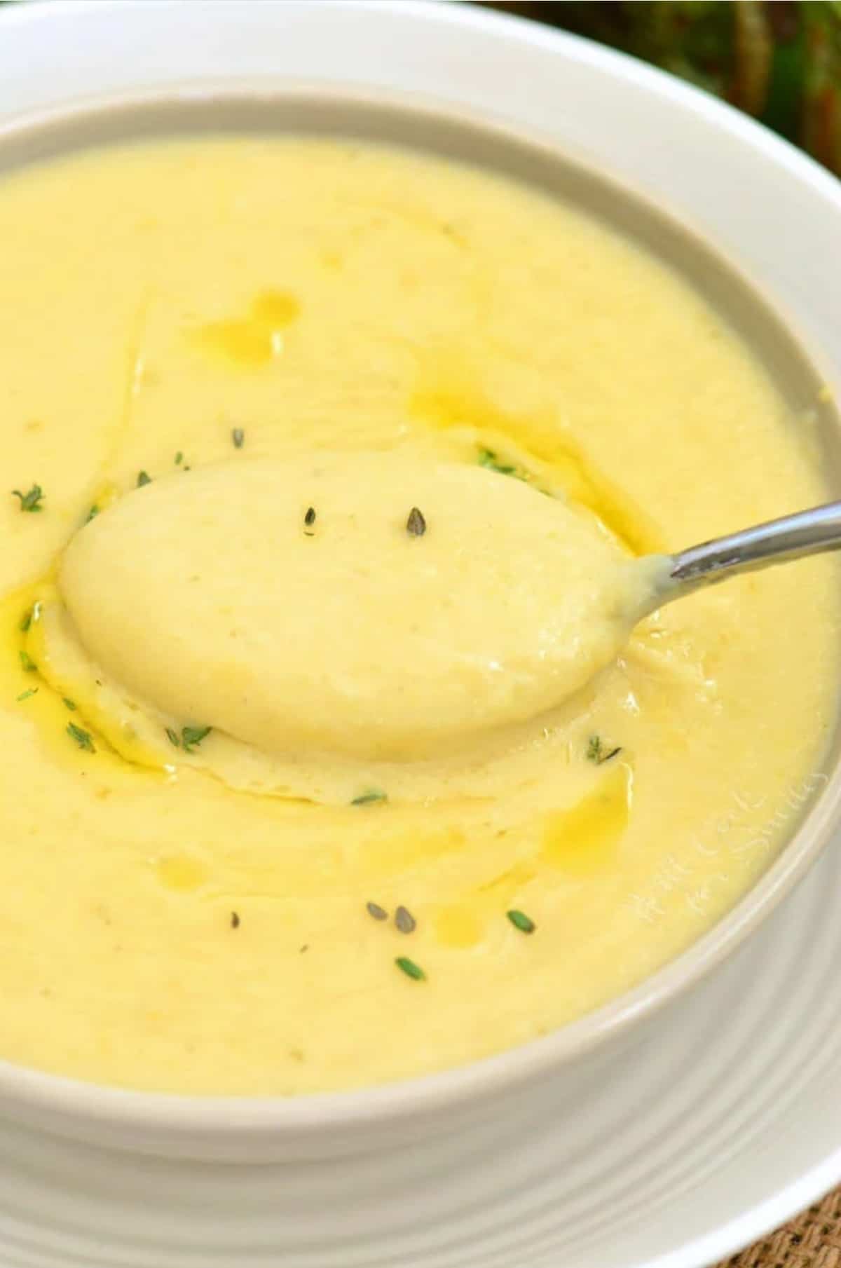 Potato leek soup in a bowl with a spoon scooping some up.