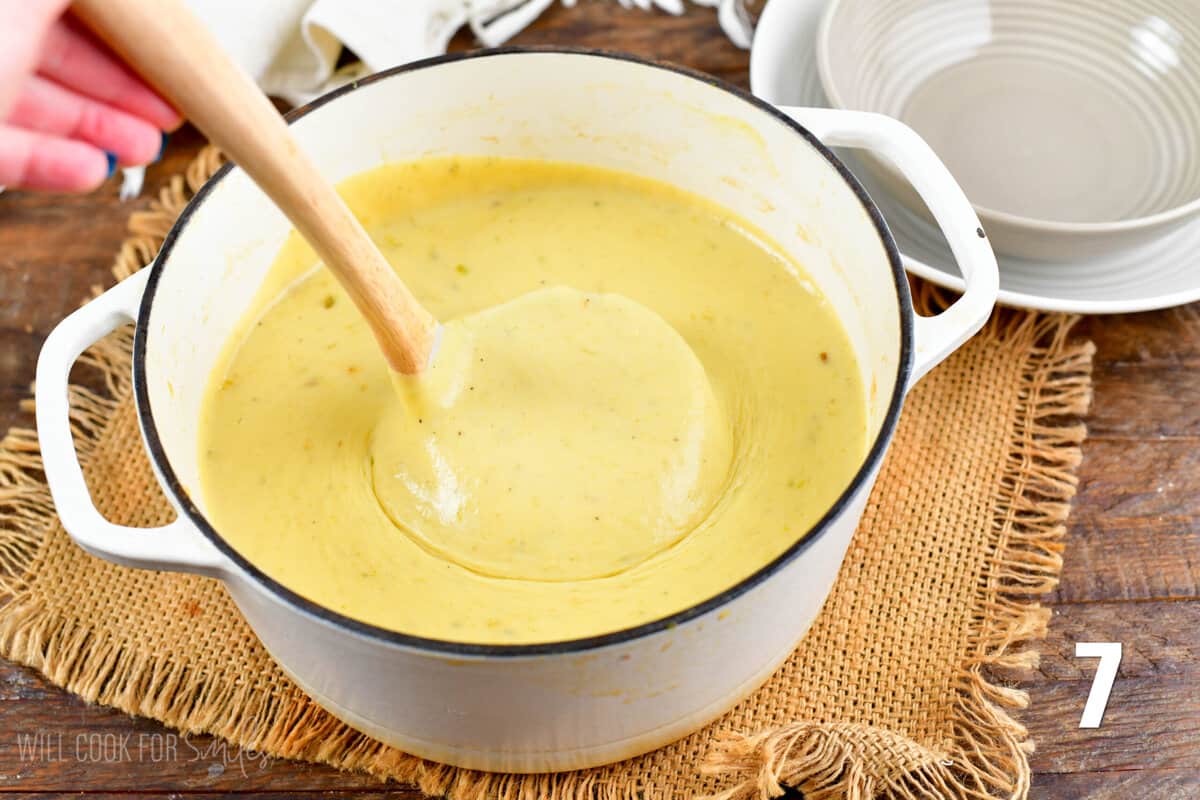 Scooping up potato leek soup with a ladle out of a pot.