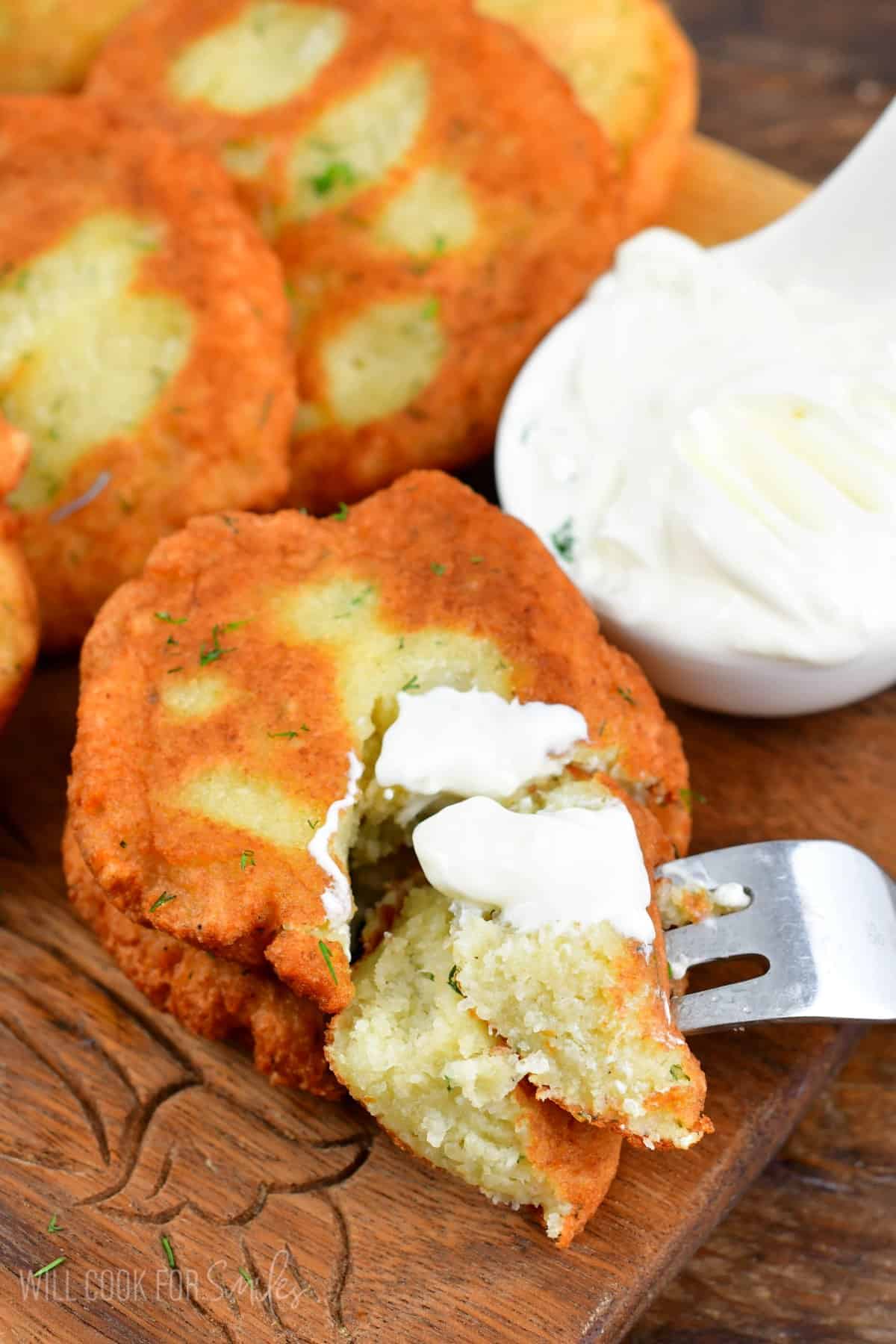 Cutting into the potato pancake with a little sour cream on top.