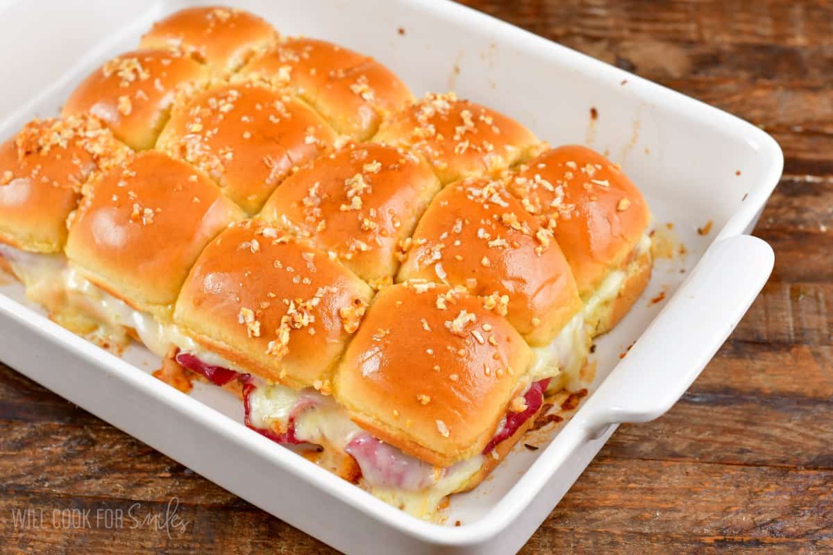 Rueben sliders baked in a baking dish on a wood surface.