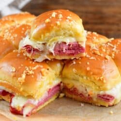 One reuben slider stacked on top of the rest of the sliders parchment paper.