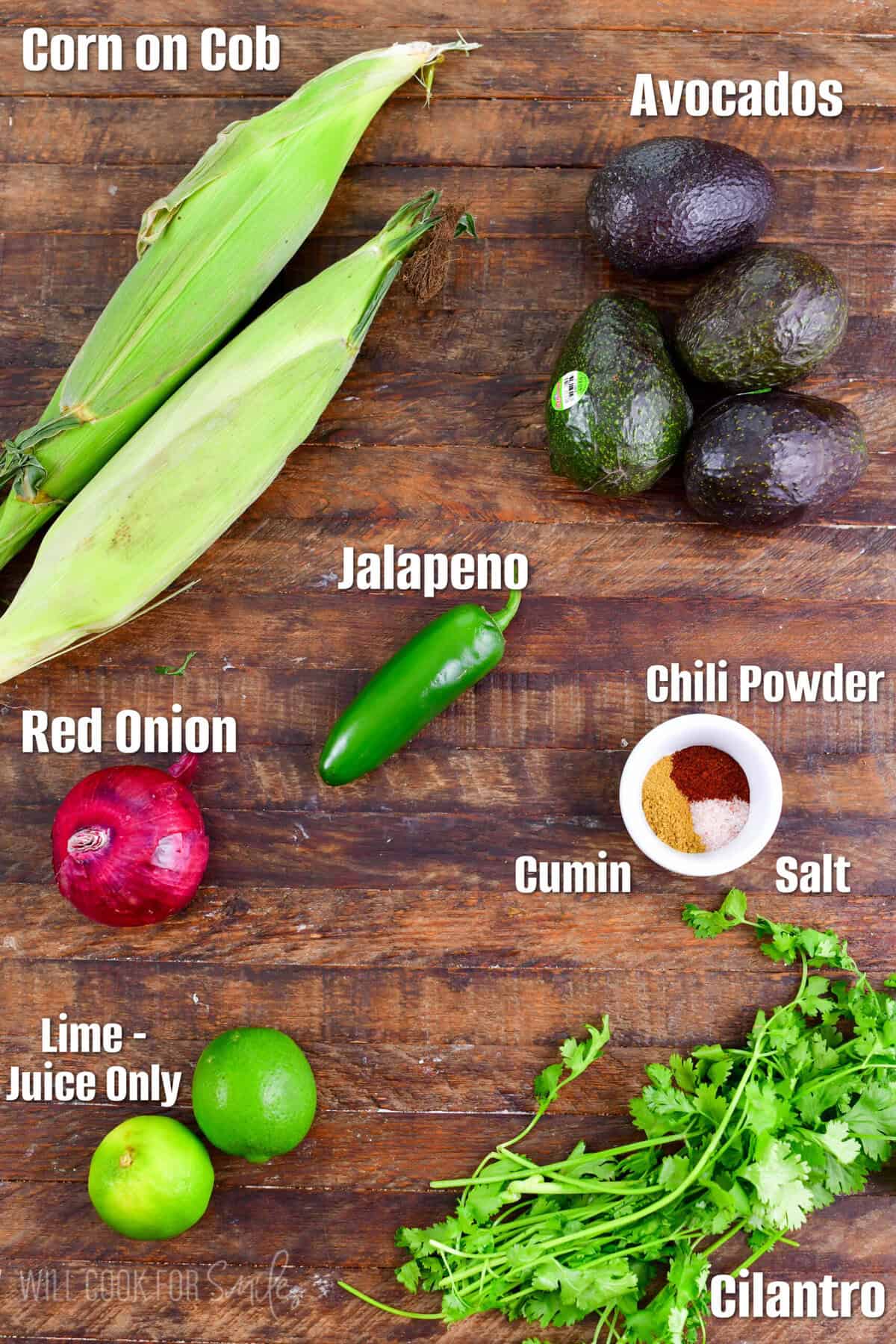 labeled ingredients for avocado salsa on a wood surface.