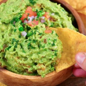 scooping out some guacamole with a tortilla chip.