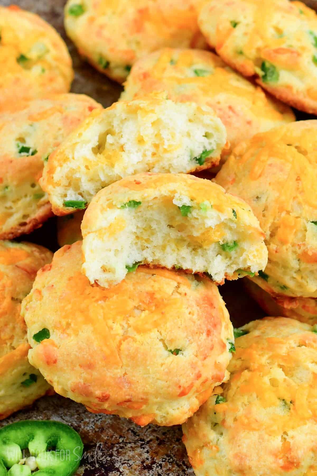 Jalapeno Cheddar biscuits stacked on top of each other with one biscuit split in half.