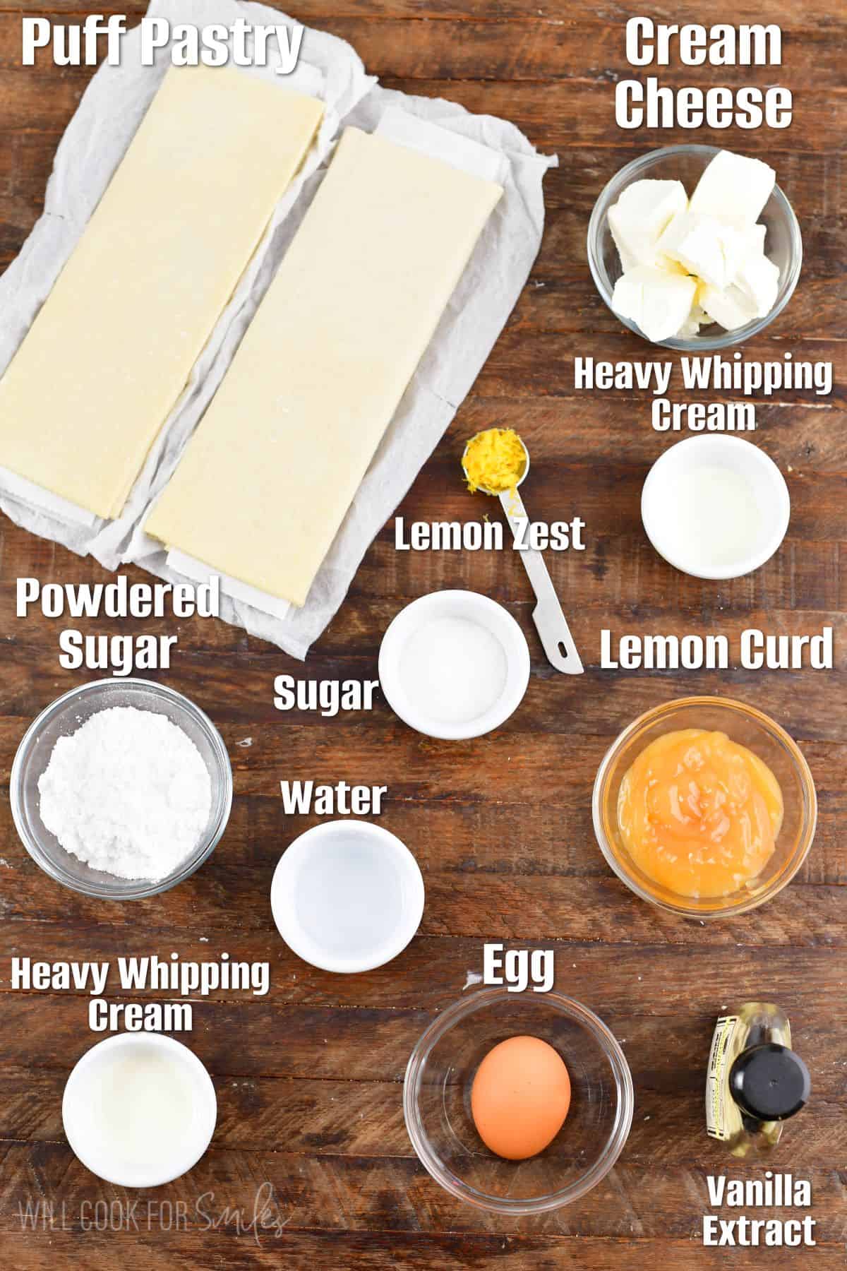 Labeled ingredients for lemon cheesecake hand pies on a wood surface.