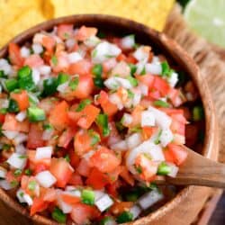 Pico de Gallo in a bowl with a wooden spoon starting to scoop some out.