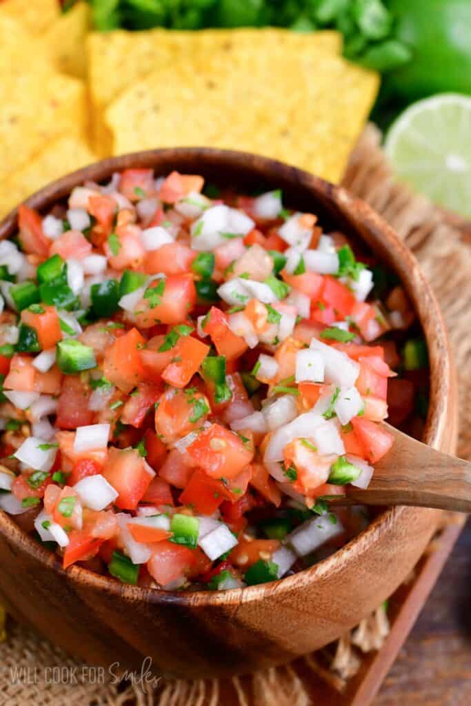 Pico de Gallo in a bowl with a wooden spoon starting to scoop some out.