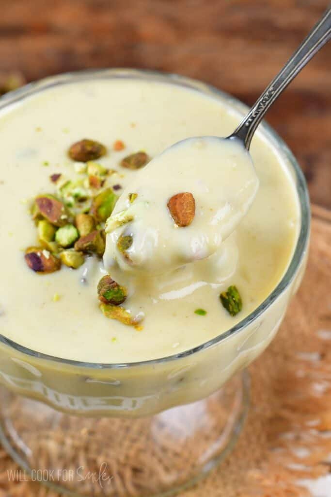 pistachio pudding in a bowl and a spoon scooping some out.