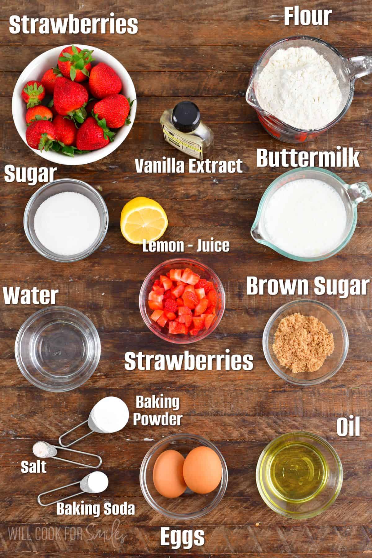 Labeled Ingredients for strawberry pancakes on a wood surface.