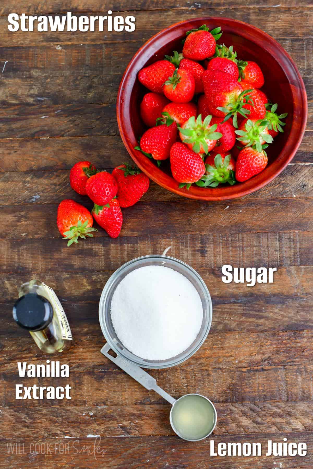 Labeled ingredients for strawberry sauce on a wood surface.