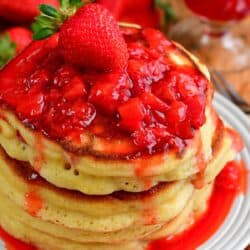 strawberry pancakes with strawberry topping and a whole strawberry on top.